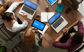 A group of people using computers on a desk. 