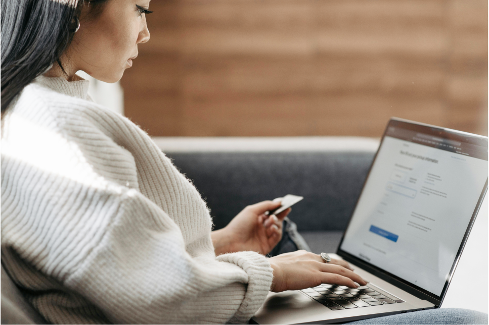 Woman viewing credit card with her laptop.