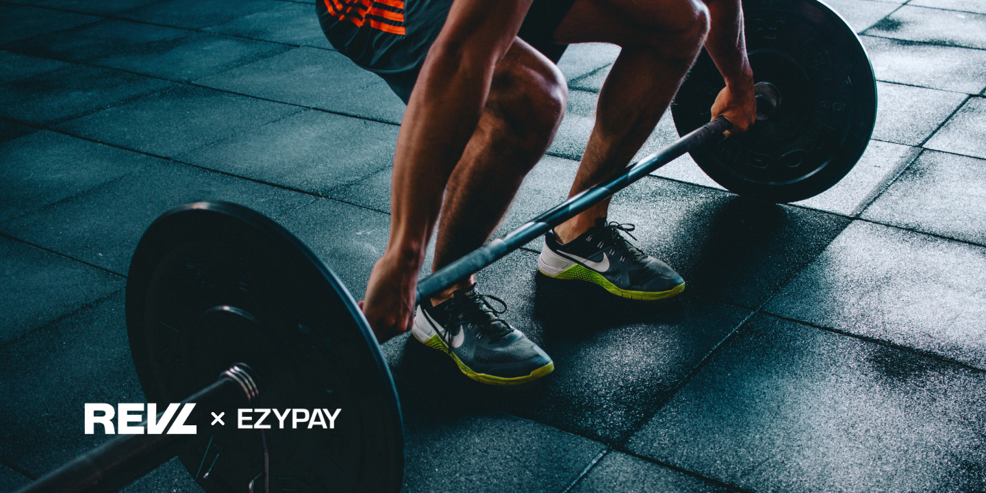 A person squatting, about to lift a large weight. They are wearing trainers. Beside the image, two logos sit: one for Ezypay and one for REVL training